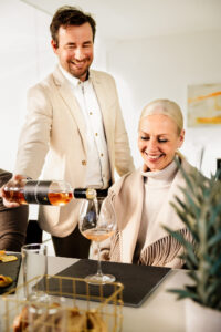 Patrick Bayer mit Rosé Zeitlos in der Hand während er diesen Wein einer blonden Dame ins Glas gibt