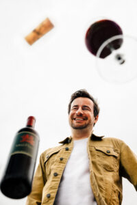 Patrick Bayer mit einem Glas Blaufränkisch In Signo Sagittarii und der In Signo Sagittarii Weinflasche