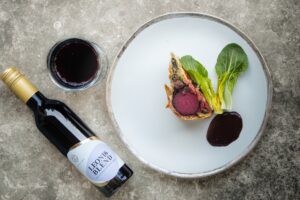 Beet Wellington mit einer Flasche Zeronimo Leonis Blend und einem Rotweinglas daneben