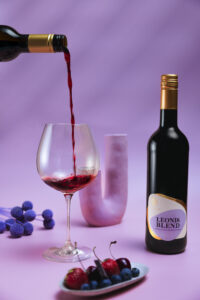 Alkoholfreier Premium-Rotwein wird in ein Weinglas eingeschenkt. Daneben steht die Flasche Zeronimo Leonis Blend